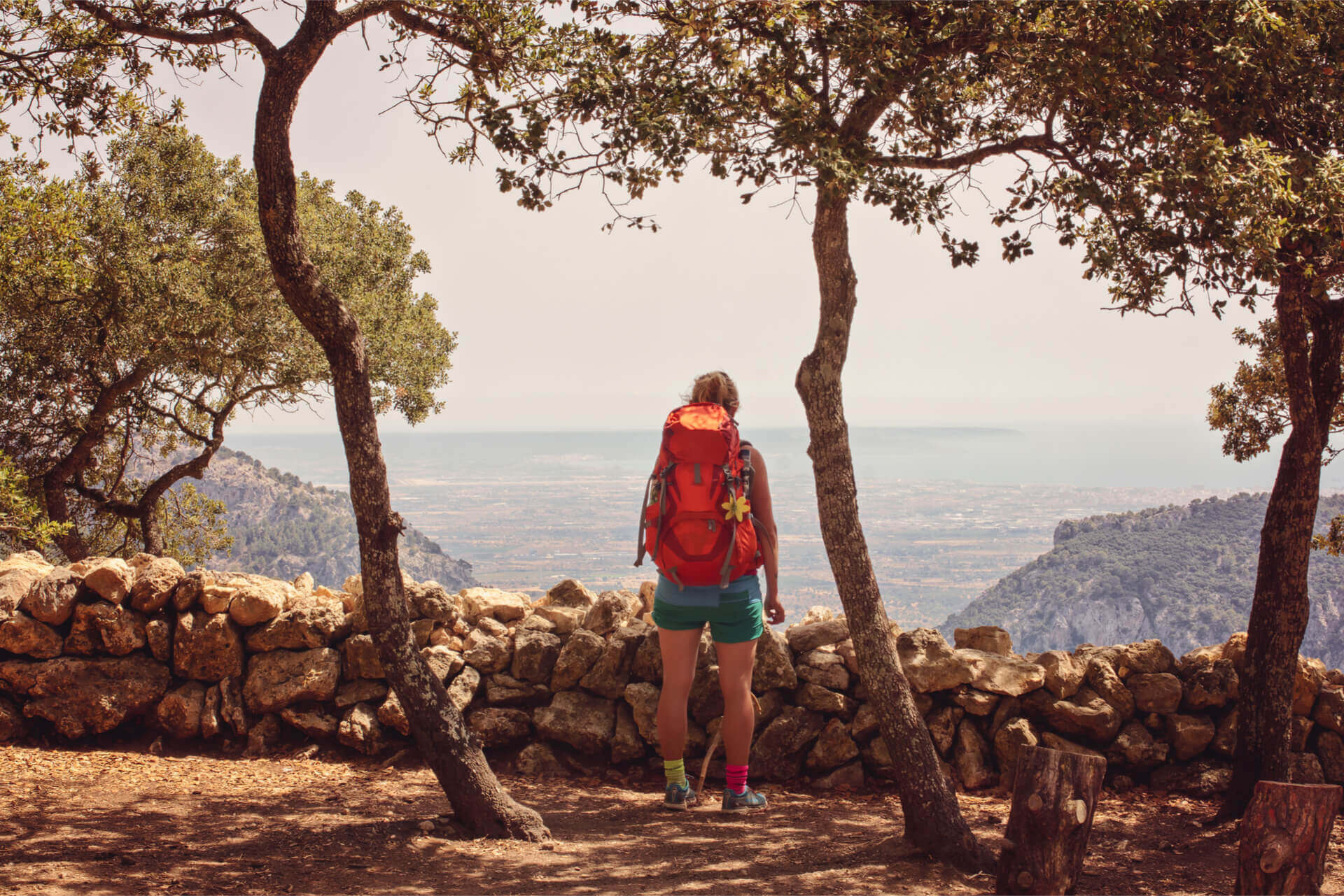Hike GR221 tourist girl orange backpack enjoys view